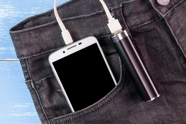 Mobile phone portable battery recharging a smartphone on jeans
