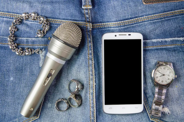 Smartphone, bracelet, Ring, watch and microphone on jeans backgr