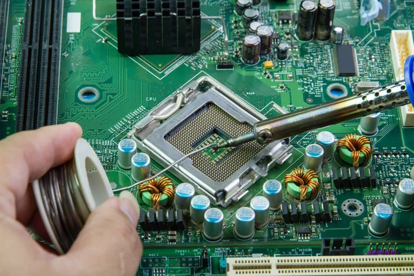 Soldering iron and microcircuit.Computer motherboard repair