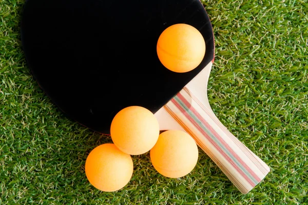 Table tennis racket and ball on grass.