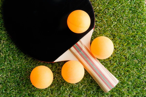 Table tennis racket and ball on grass.