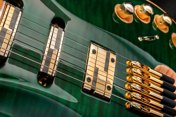 Green six-string electric guitar close up on dark background