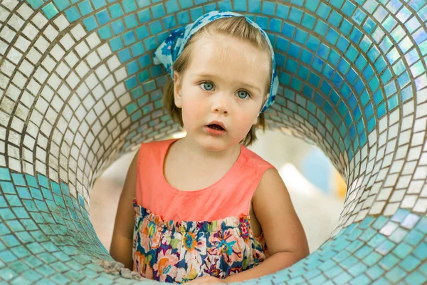 Little girl with a bandage on his head in the game round figure on the playground, playing with sand.