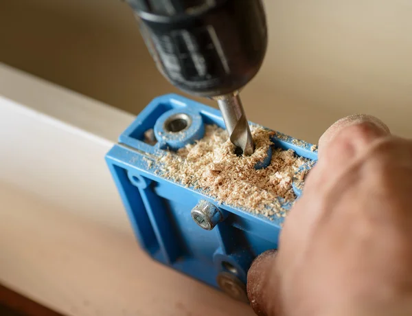 Furniture assembly. Master drills drill a hole in the furniture board.