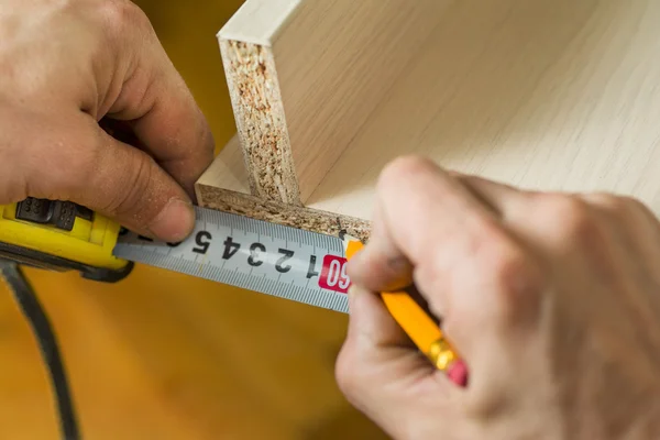 Furniture assembly. Master ruler measure the size of the furniture on board