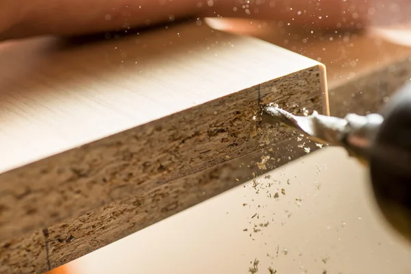 Furniture assembly. Master drills drill a hole in the furniture board.