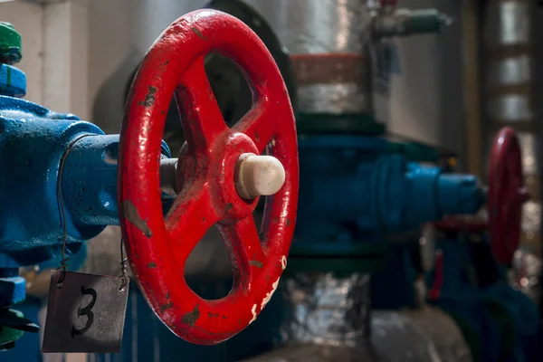 Red valve on the pipe in the boiler room