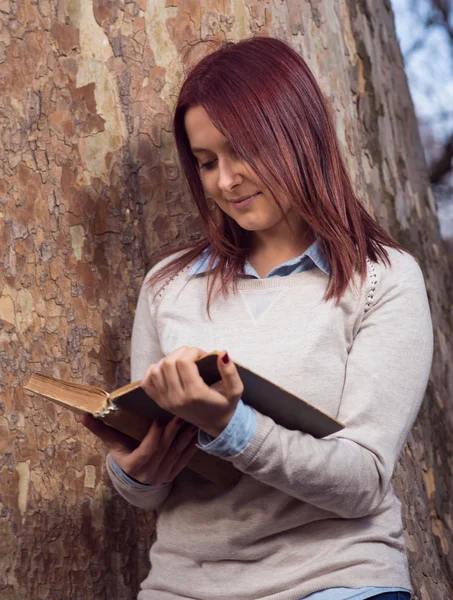 University girl in park reading a book