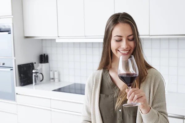 Woman in kitchen enjoying glass of wine