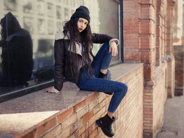 Outdoor lifestyle fashion portrait of pretty young girl, wearing in hipster swag grunge style on urban background. Wearing hat and jeans. Spring fashion woman. Toned style instagram filters.