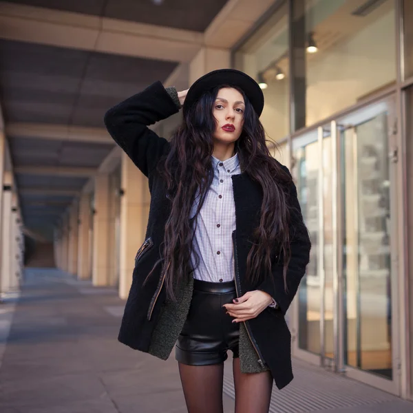 Outdoor lifestyle fashion portrait of pretty young girl, wearing in boho grunge style on urban background. Wearing hat and coat. Spring fashion woman. Toned style instagram filters
