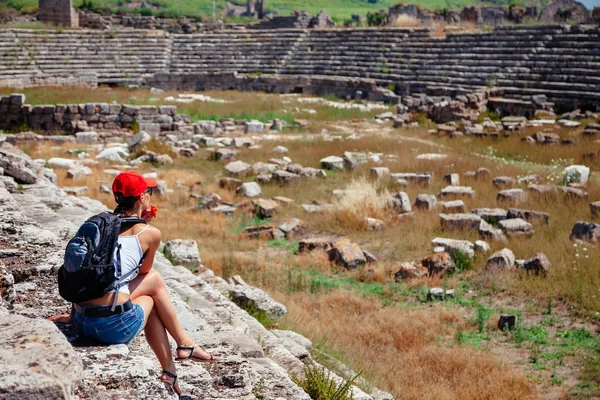 Pretty tourist woman with backpack at the ruins of ancient city of Perge near Antalya Turkey