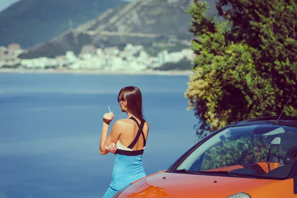 Beautiful young woman looking and waiting at the seacoast. Sunny day. Montenegro, Europe. Retro style toning image.