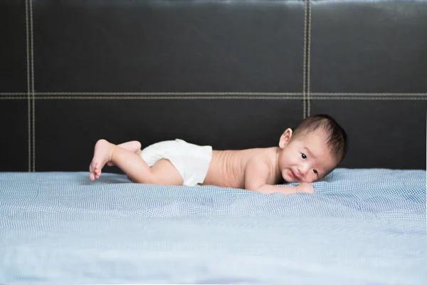 Cute Asian baby lying on a white pillow, on bed