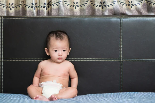 Cute Asian baby sitting on bed, Shallow DOF, focus on eyes.