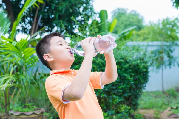 Asian boy drinking water from bottle