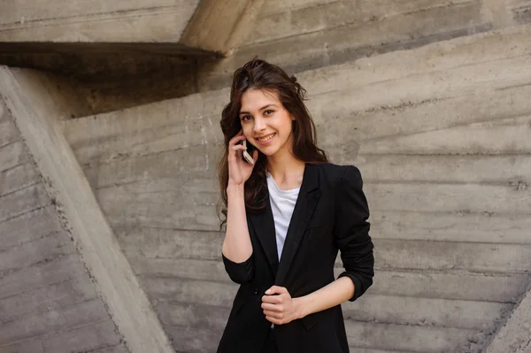 Young happy girl talking on phone , looking at the camera