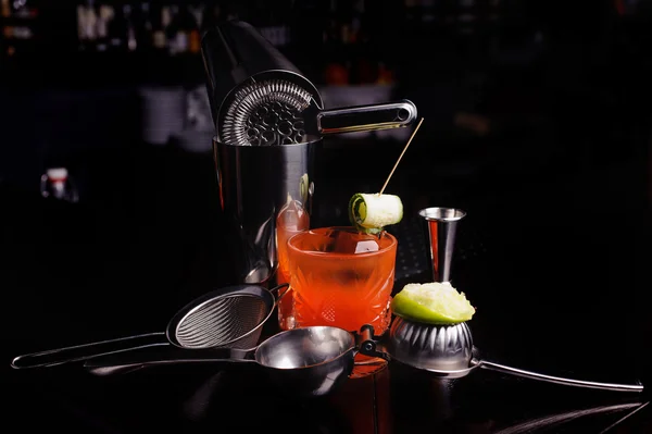 Red cocktail drink with ice.  bar tools and shaker.