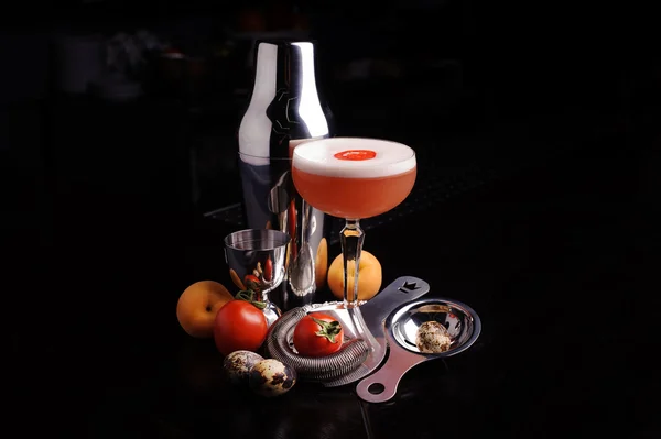 Red cocktail drink with ice. bar tools and shaker.