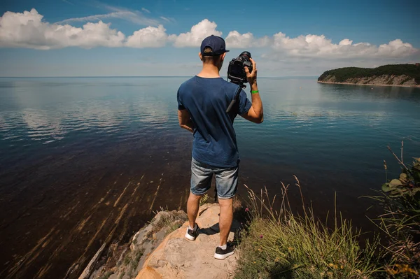 Man from behind photographing lake