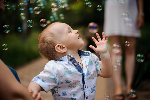 Boy playing catch soap bubbles outdoors