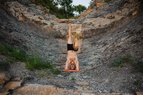 Male relax while doing yoga exercises head stand