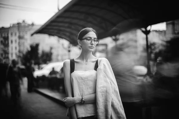 Pretty young brunette woman dressed casual posing outdoor with leather handbag. black and white photo