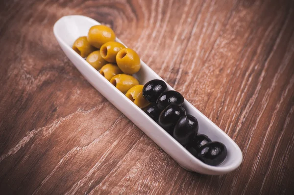 Green and black olives in white plate