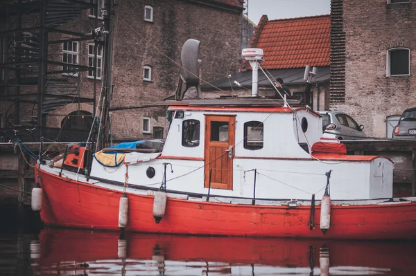 Small red  wooden motor boat tethered on the river dart