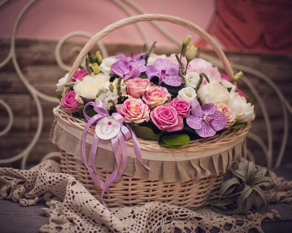 Beautiful bouquet of pink flowers in basket on decorated table