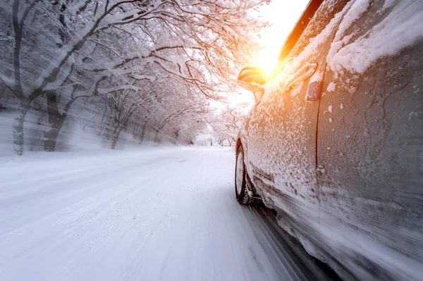 Car and falling snow in winter on forest road with much snow.(Motion blur)