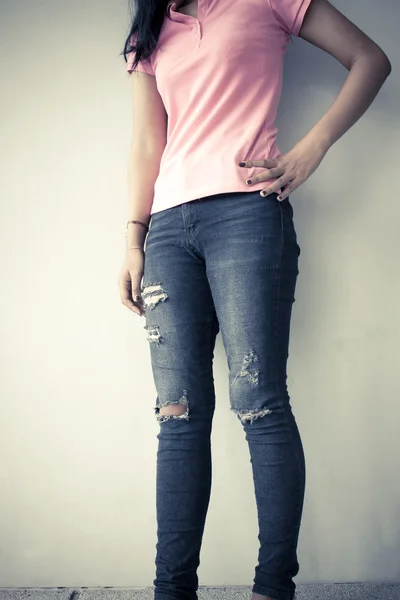 Young fashion woman legs in jeans, vintage tone background