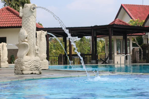 Fountain in the form of fish in a public pool in Bali. Indonesia fountain in the form of fish in a public pool with technical building in the background