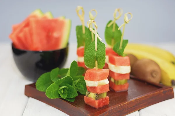 Sandwich of watermelon, kiwi and banana with a mint leaf.