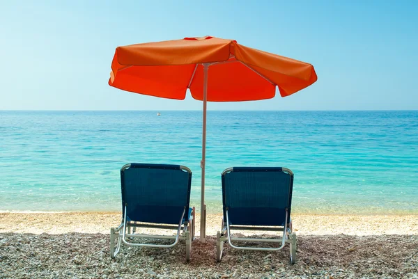 Blue sunbeds and orange umbrella (parasol) on Paradise Beach in