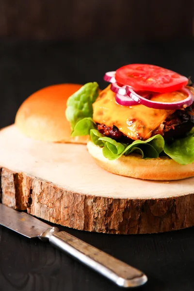 Delicious fresh homemade burger on dark serving board with spicy