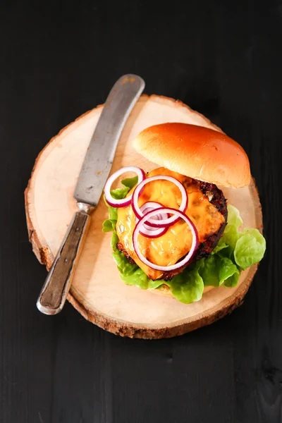 Delicious fresh homemade burger on dark serving board with spicy