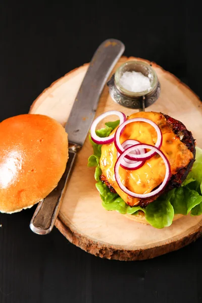 Delicious fresh homemade burger on dark serving board with spicy