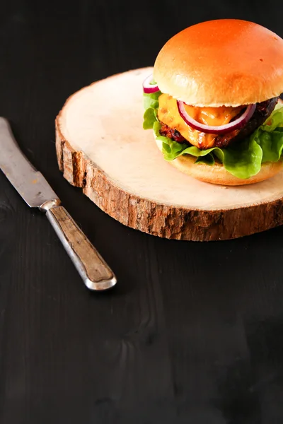 Delicious fresh homemade burger on dark serving board with spicy