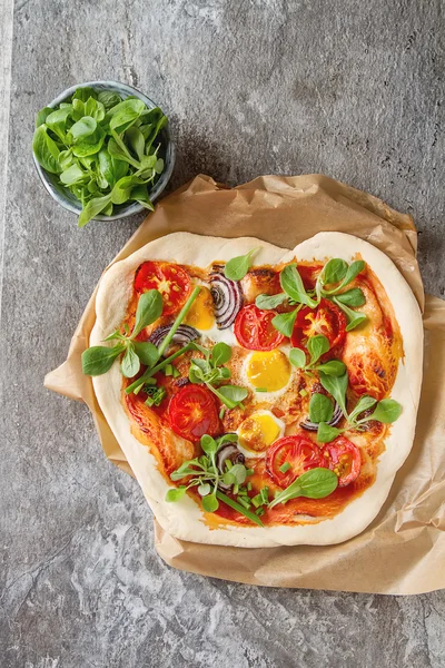 Home Italian pizza with tomato and quail eggs salad on a baking