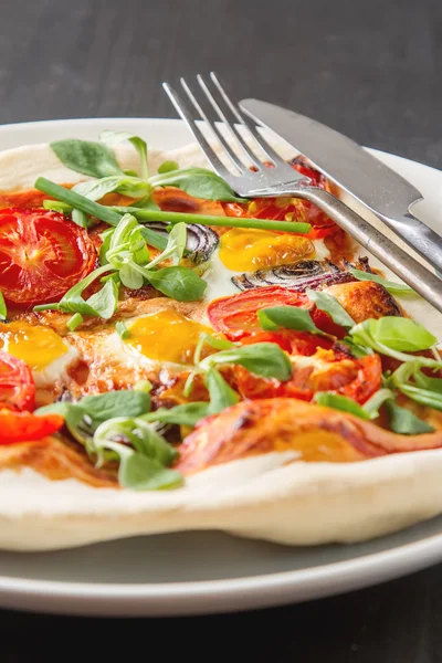 Home Italian pizza with tomato and quail eggs salad on a white p
