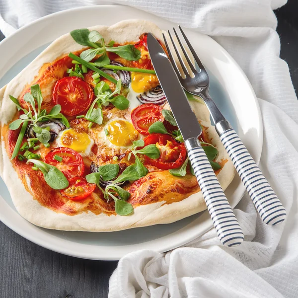 Home Italian pizza with tomato and quail eggs salad on a white p