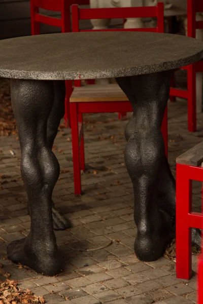 Red designer chairs and a table in the form of human feet