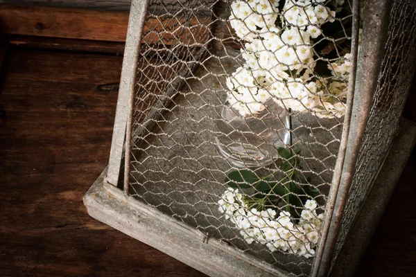 Flowers in a vase in a cage for birds. on a wooden background
