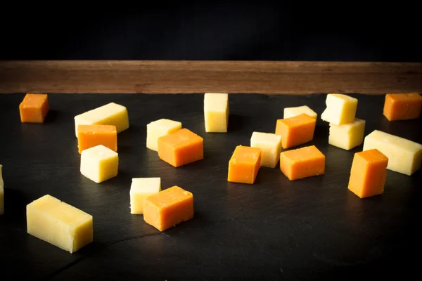 Yellow and white cheddar cheese on a black background