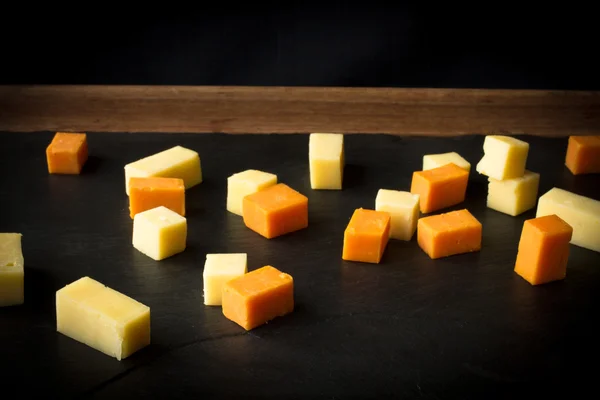 Yellow and white cheddar cheese on a black background