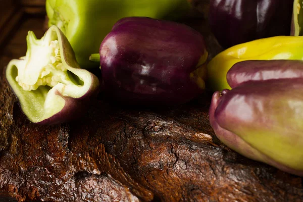 Purple and green pepper on a wooden background