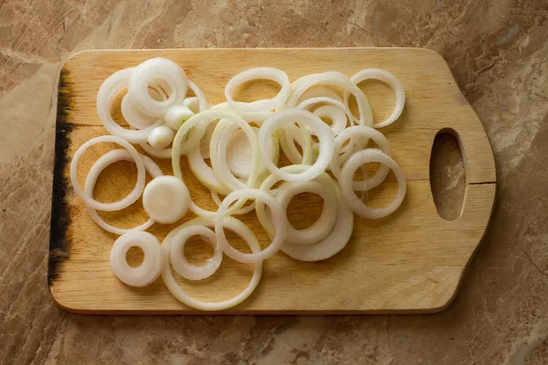 White onion rings lie on a marble background