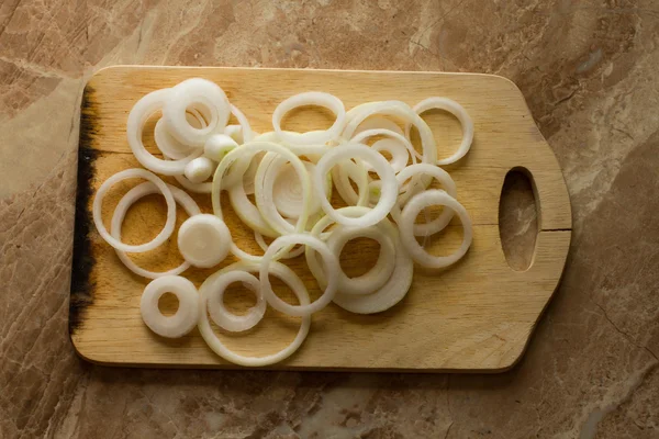 White onion rings lie on a marble background