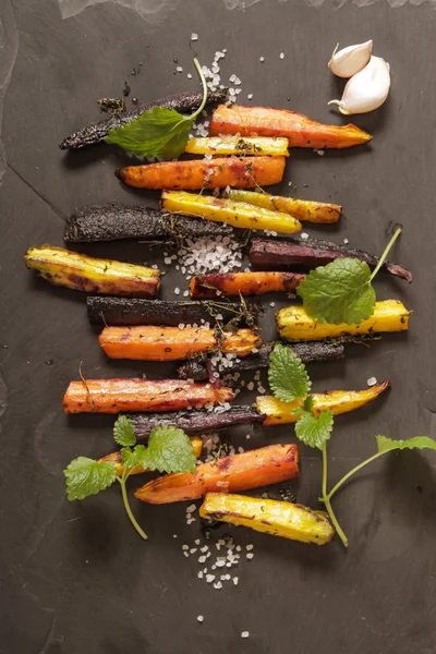 Baked colorful carrots on a black background